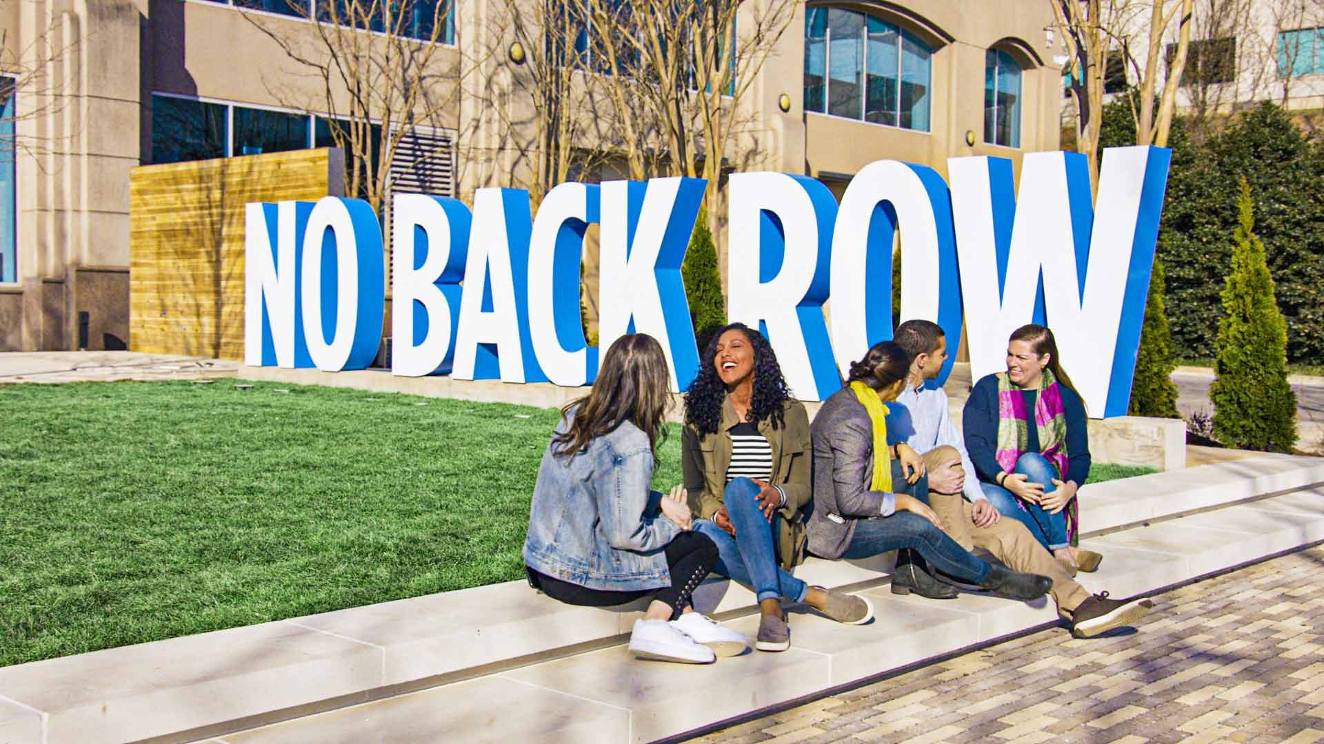 Group of students sitting on a ledge outside an academic building