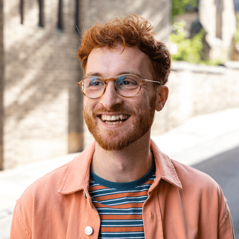 Man in glasses and orange shirt staring forward